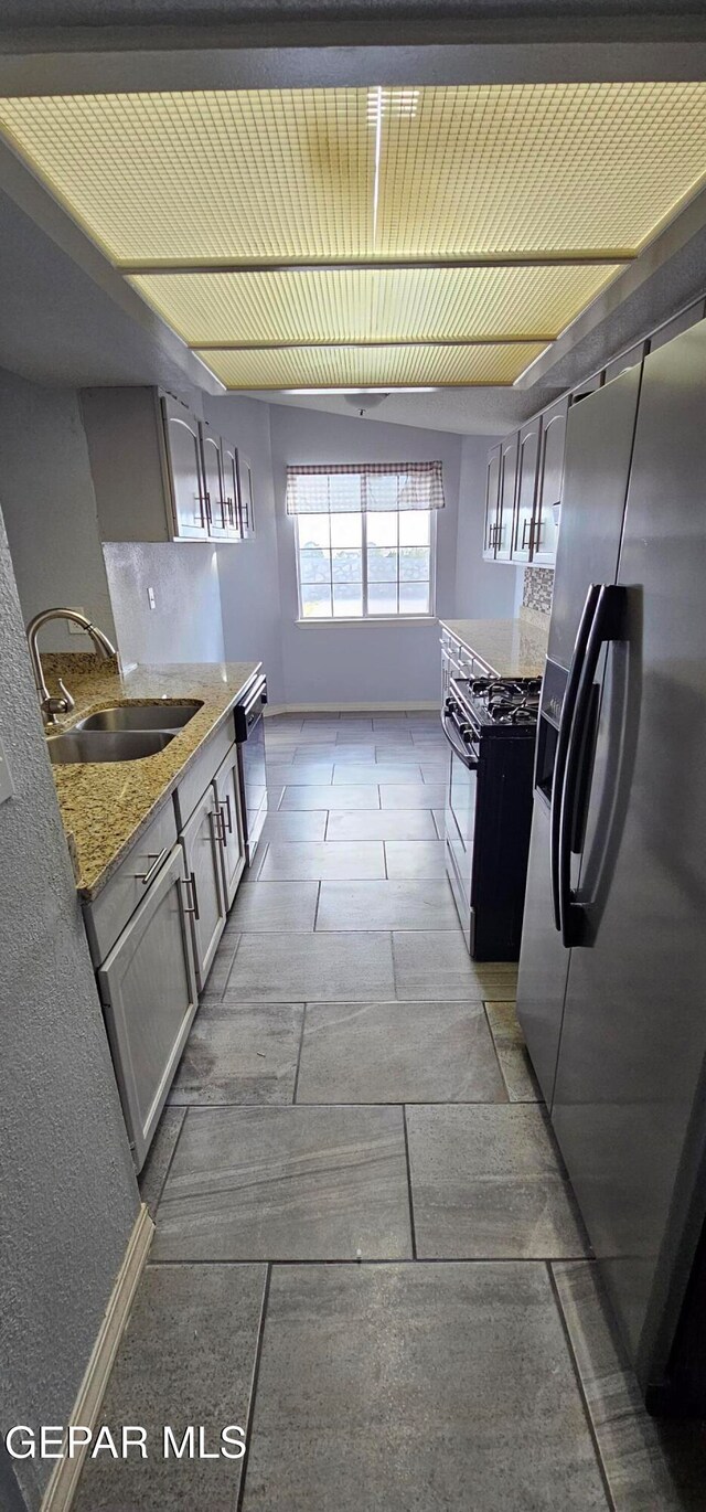 kitchen with light stone countertops, sink, and stainless steel appliances