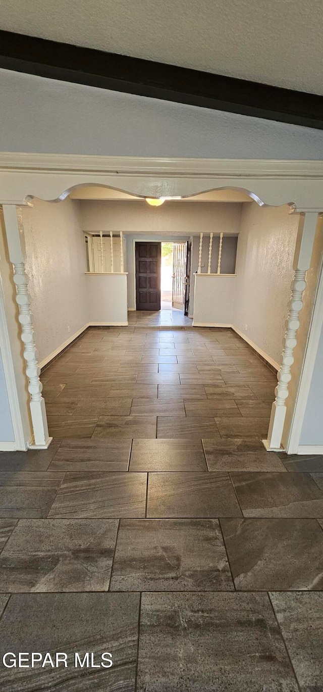 corridor featuring beamed ceiling and a textured ceiling