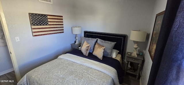 bedroom with visible vents, baseboards, and wood finished floors