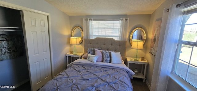 bedroom featuring a textured ceiling, baseboards, and wood finished floors