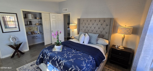 bedroom with baseboards, visible vents, dark wood finished floors, and a closet