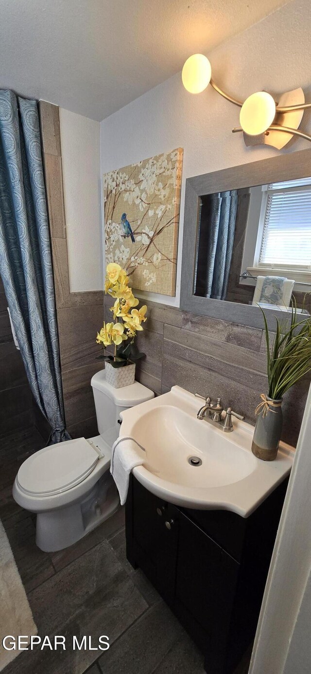 bathroom featuring tile walls, vanity, and toilet