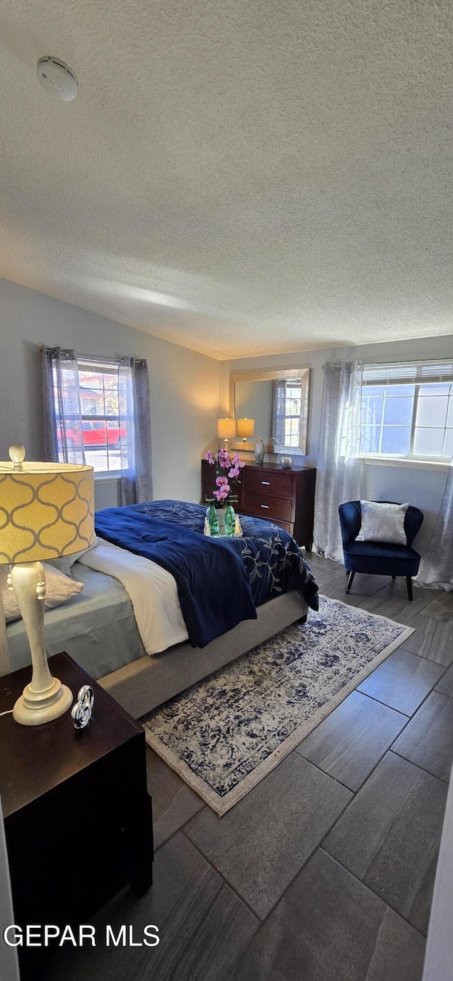 bedroom with a textured ceiling, multiple windows, and wood finished floors