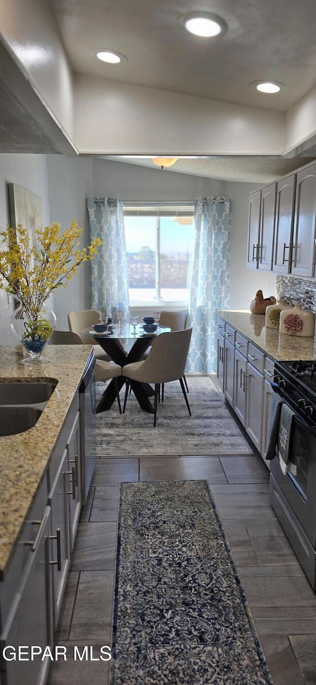 kitchen featuring light stone counters, gas stove, stainless steel dishwasher, and recessed lighting