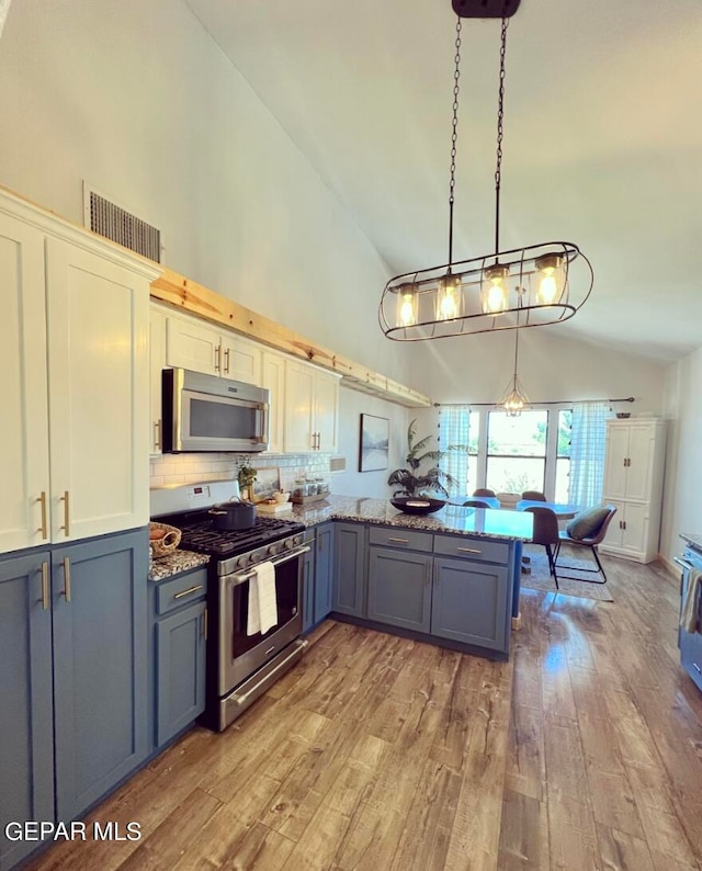 kitchen featuring kitchen peninsula, hanging light fixtures, white cabinetry, light hardwood / wood-style floors, and stainless steel appliances