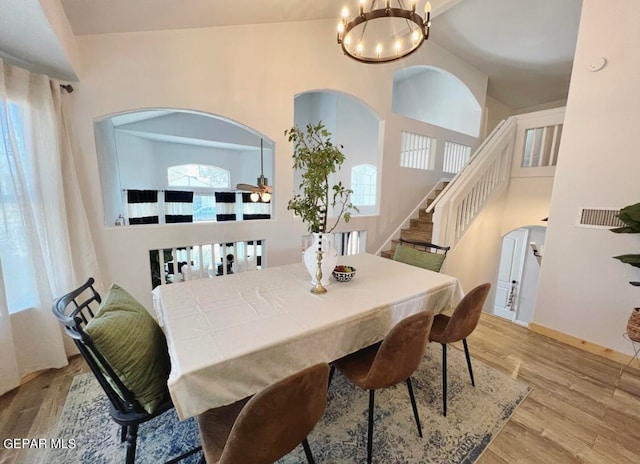 dining area with high vaulted ceiling, light hardwood / wood-style flooring, and a chandelier