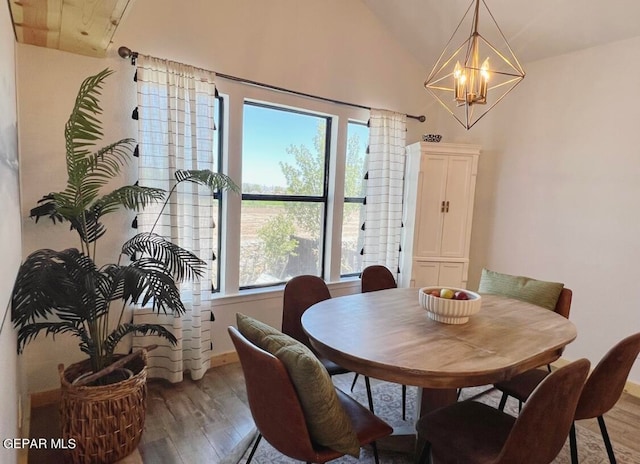 dining area featuring a notable chandelier, wood-type flooring, vaulted ceiling, and plenty of natural light