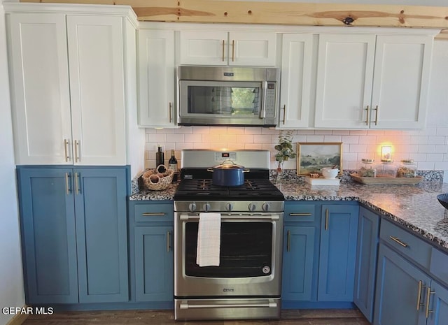 kitchen with appliances with stainless steel finishes, decorative backsplash, white cabinets, and blue cabinets