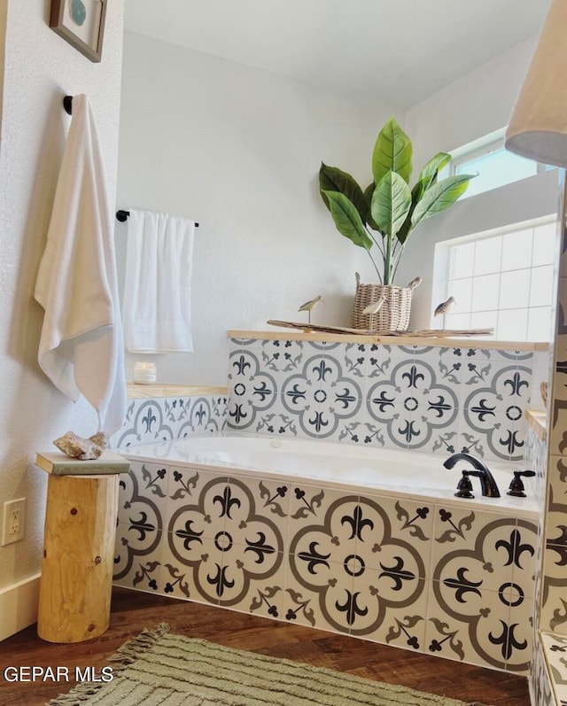 bathroom featuring hardwood / wood-style flooring and tiled tub