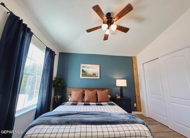 bedroom with a closet, ceiling fan, hardwood / wood-style flooring, and vaulted ceiling