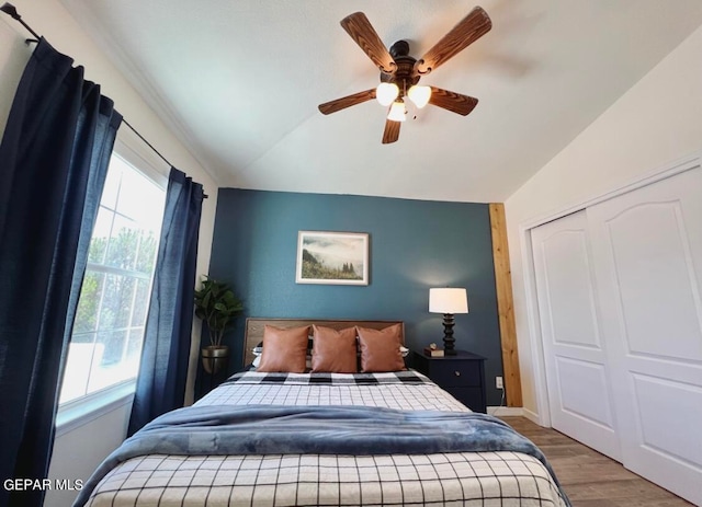 bedroom with lofted ceiling, a closet, light hardwood / wood-style floors, and ceiling fan