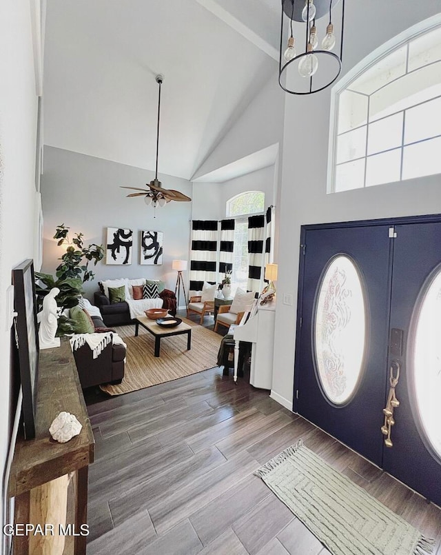 foyer entrance featuring hardwood / wood-style flooring, high vaulted ceiling, and ceiling fan with notable chandelier