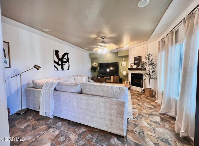 living room featuring ceiling fan and a fireplace