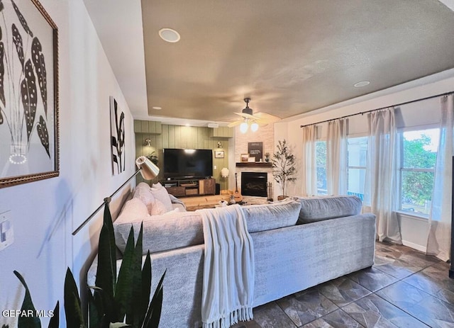 living room featuring ceiling fan and a fireplace