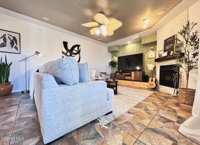 living room featuring ceiling fan and a fireplace