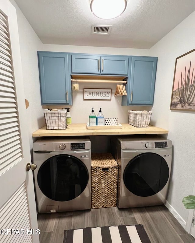 clothes washing area with cabinets, a textured ceiling, separate washer and dryer, and dark hardwood / wood-style flooring