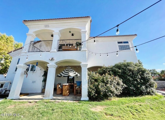 rear view of property with a patio area, a lawn, and a balcony