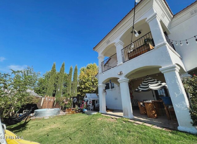 exterior space with a balcony, a patio area, and a lawn