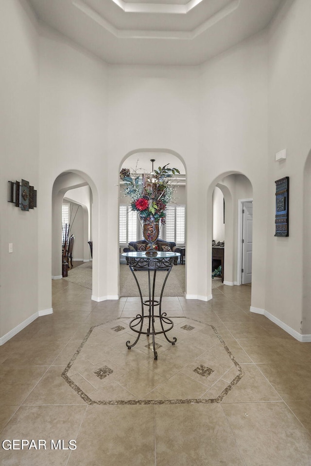 tiled entryway with a high ceiling and a notable chandelier