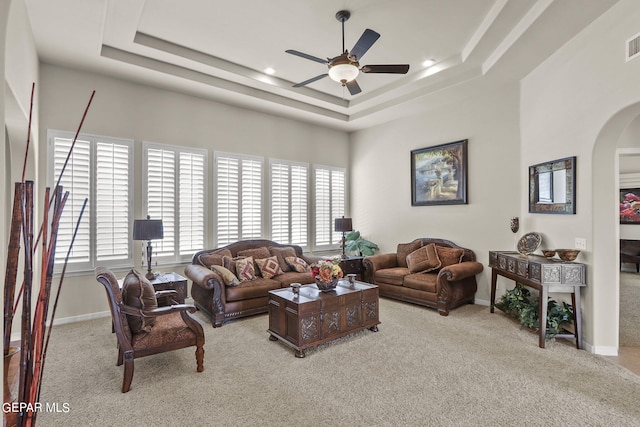 living room featuring ceiling fan, a raised ceiling, and light carpet