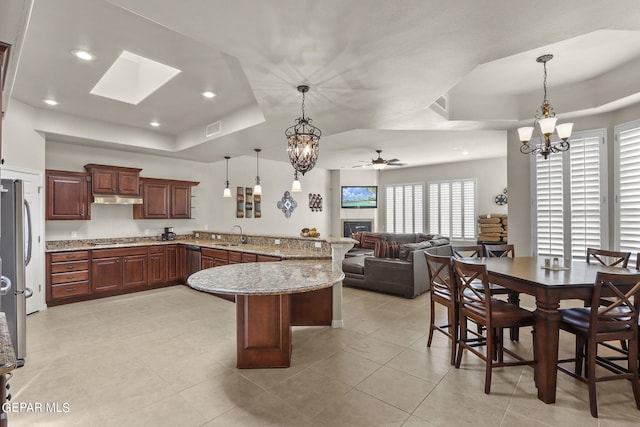 kitchen with ceiling fan with notable chandelier, decorative light fixtures, and a raised ceiling