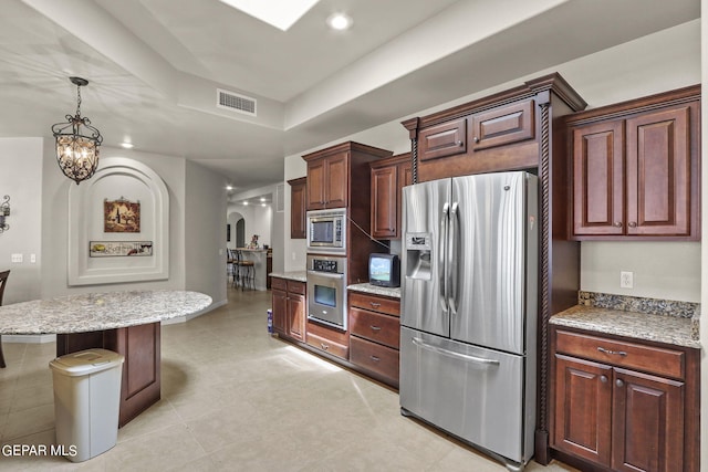 kitchen featuring a center island, a notable chandelier, decorative light fixtures, a breakfast bar area, and appliances with stainless steel finishes