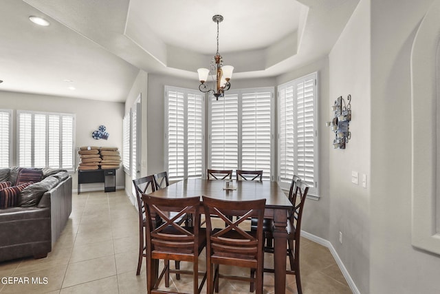 tiled dining area featuring a tray ceiling and an inviting chandelier