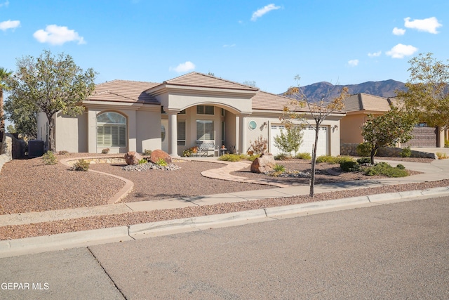 mediterranean / spanish home with central AC unit, a garage, and a mountain view