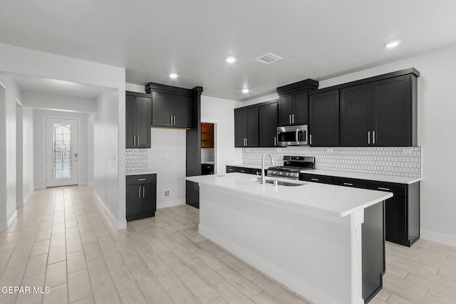 kitchen featuring light hardwood / wood-style flooring, appliances with stainless steel finishes, sink, and a kitchen island with sink