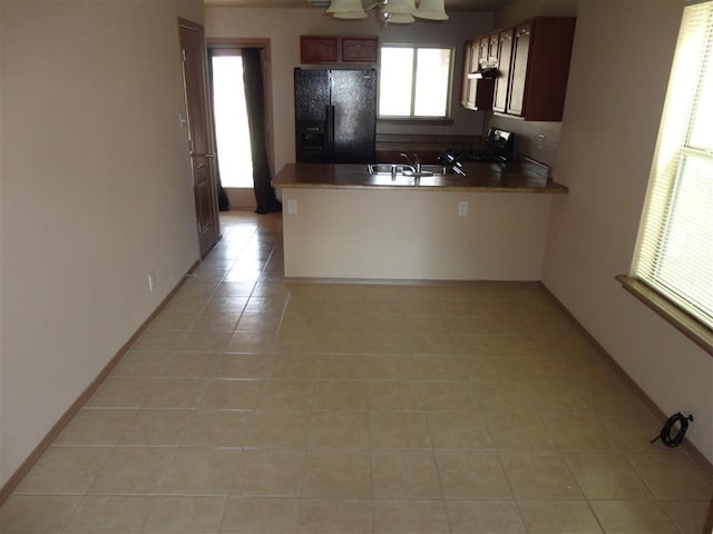 kitchen with kitchen peninsula, black appliances, sink, and light tile patterned flooring