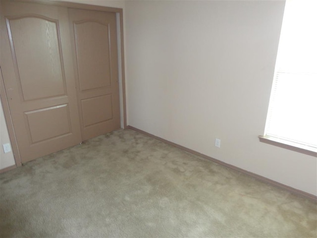 unfurnished bedroom with light colored carpet and a closet