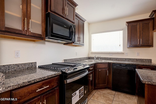 kitchen featuring dark brown cabinetry, black appliances, light tile patterned floors, sink, and dark stone countertops