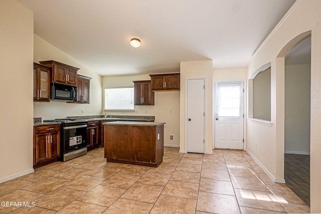 kitchen featuring a center island, dark brown cabinetry, light tile patterned floors, sink, and stainless steel stove