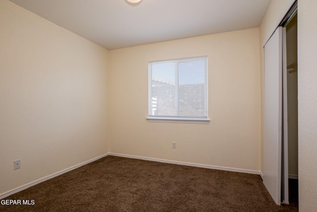 unfurnished bedroom with a closet and dark carpet