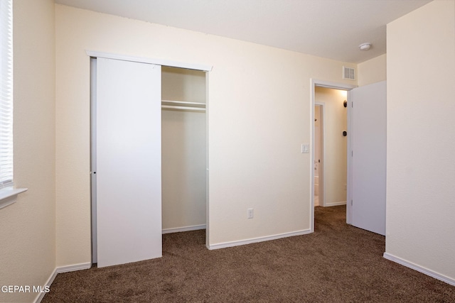 unfurnished bedroom with a closet and dark carpet