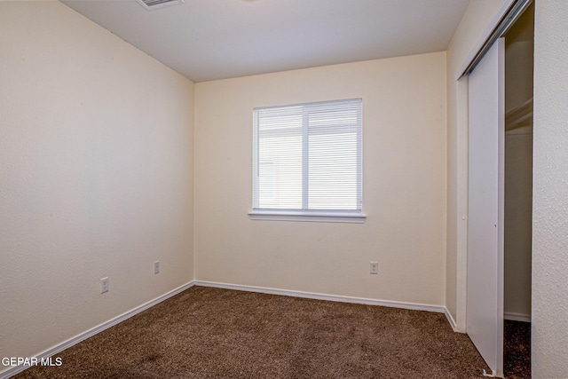 unfurnished bedroom with a closet and dark carpet