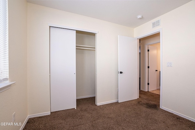 unfurnished bedroom with a closet and dark colored carpet