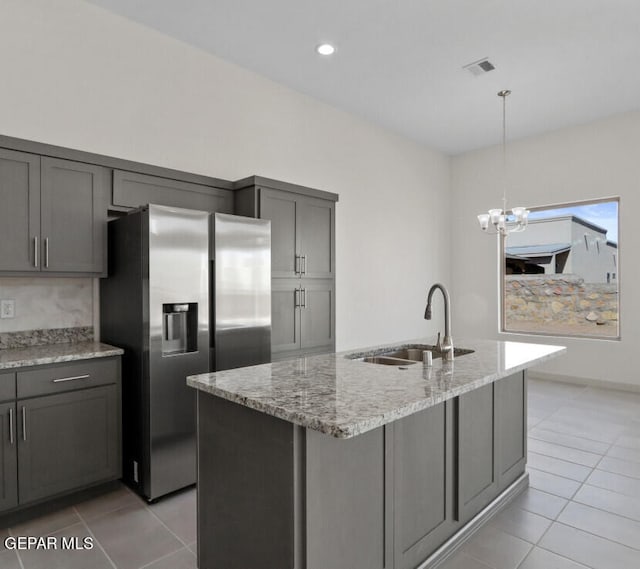 kitchen with a center island with sink, sink, stainless steel fridge with ice dispenser, and gray cabinetry