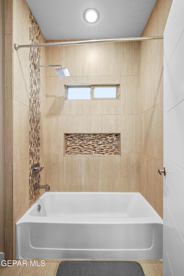 bathroom with tile walls and tiled shower / bath combo