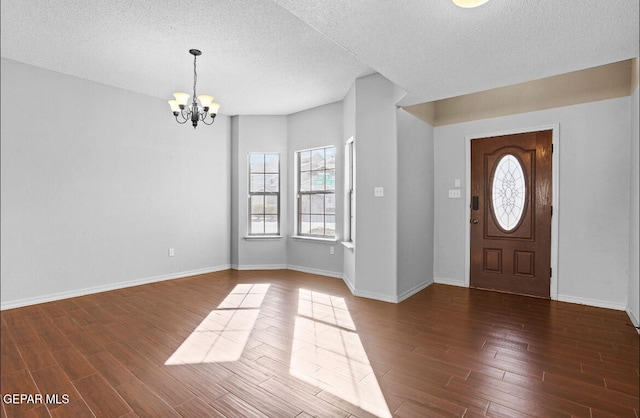 entryway featuring dark wood-type flooring, a textured ceiling, and a notable chandelier