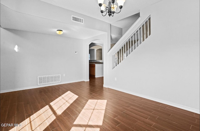 unfurnished living room featuring dark hardwood / wood-style floors and an inviting chandelier