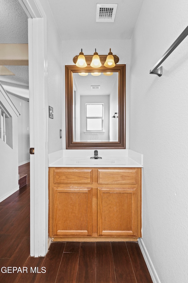 bathroom featuring vanity, wood-type flooring, and a textured ceiling