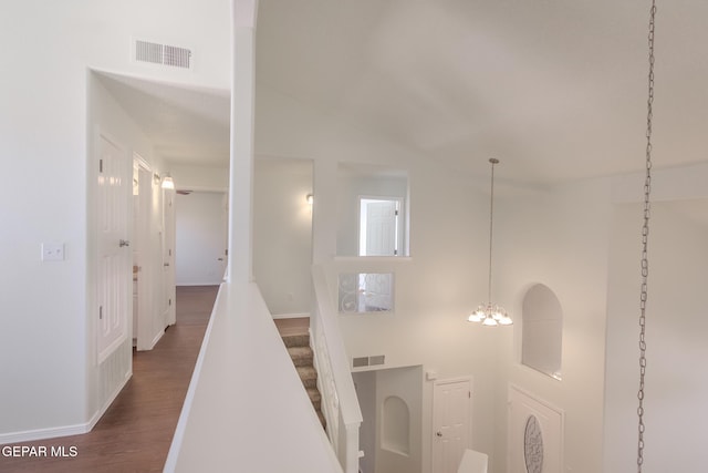 hallway with dark wood-type flooring, high vaulted ceiling, and an inviting chandelier