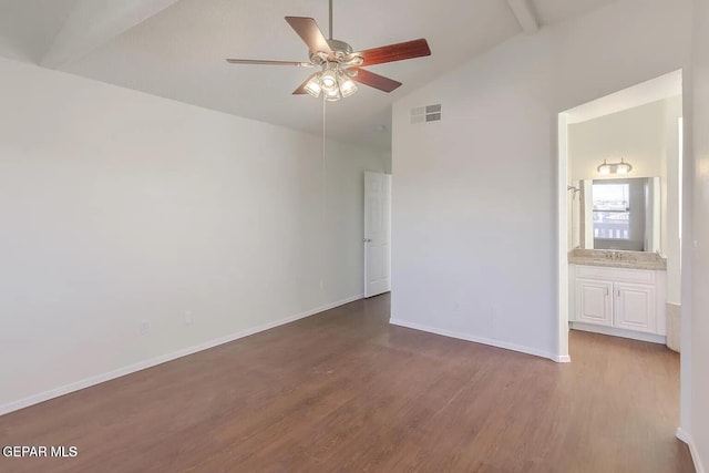 unfurnished bedroom featuring wood-type flooring, vaulted ceiling with beams, ceiling fan, and connected bathroom