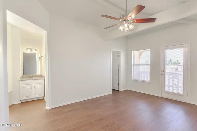 empty room with beamed ceiling, ceiling fan, and light wood-type flooring