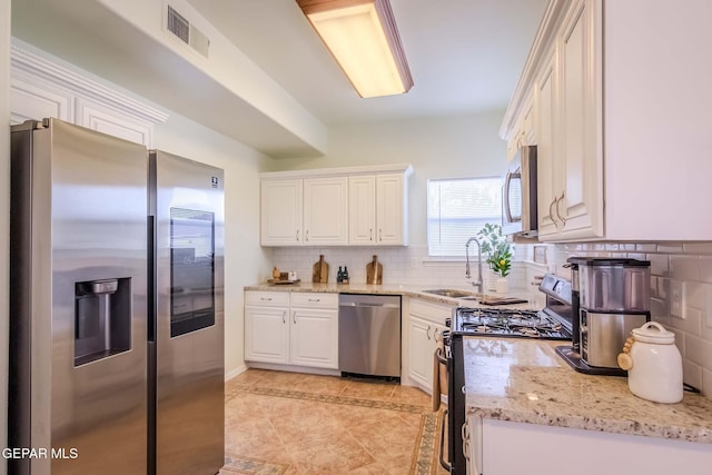 kitchen featuring white cabinets, stainless steel appliances, light stone countertops, and sink