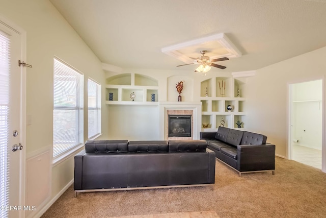 living room featuring a tile fireplace, ceiling fan, built in features, and light colored carpet