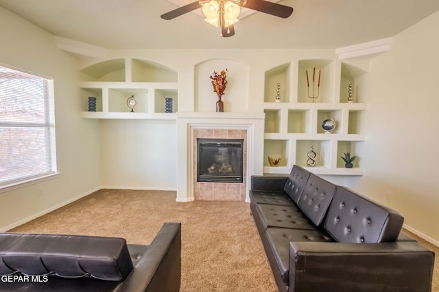 carpeted living room with a tile fireplace, ceiling fan, plenty of natural light, and built in features