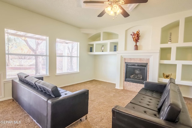 carpeted living room featuring a tile fireplace, built in features, and ceiling fan