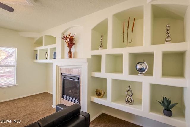 interior details featuring a textured ceiling, carpet flooring, built in features, and a fireplace